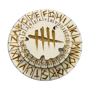 Puede incluir: Un rompecabezas circular de madera de tres niveles con letras y números grabados. La pieza central presenta un símbolo estilizado. Los anillos exteriores tienen letras y números, mientras que el centro tiene un diseño único. El rompecabezas es de madera clara.