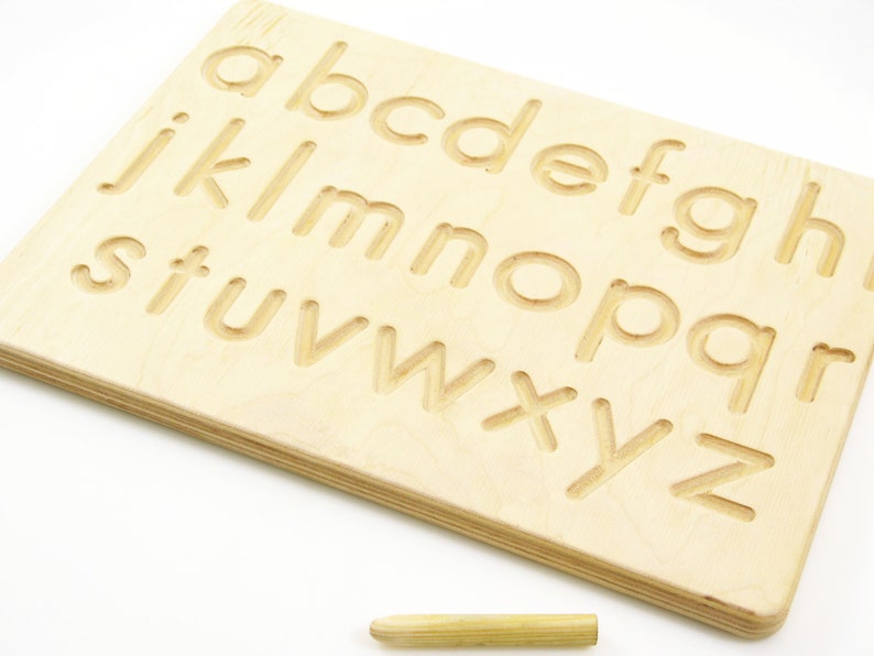 Peut inclure: Planche de tra&ccedil;age de l'alphabet en bois avec un stylet. La planche a les lettres de l'alphabet grav&eacute;es dessus, et le stylet peut &ecirc;tre utilis&eacute; pour tracer les lettres.