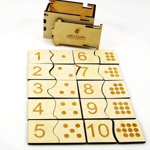 May include: Wooden Montessori number puzzle with a box. The puzzle pieces feature numbers 1 through 10 and corresponding dots. The box has the word "MONTESSORI" printed on it.