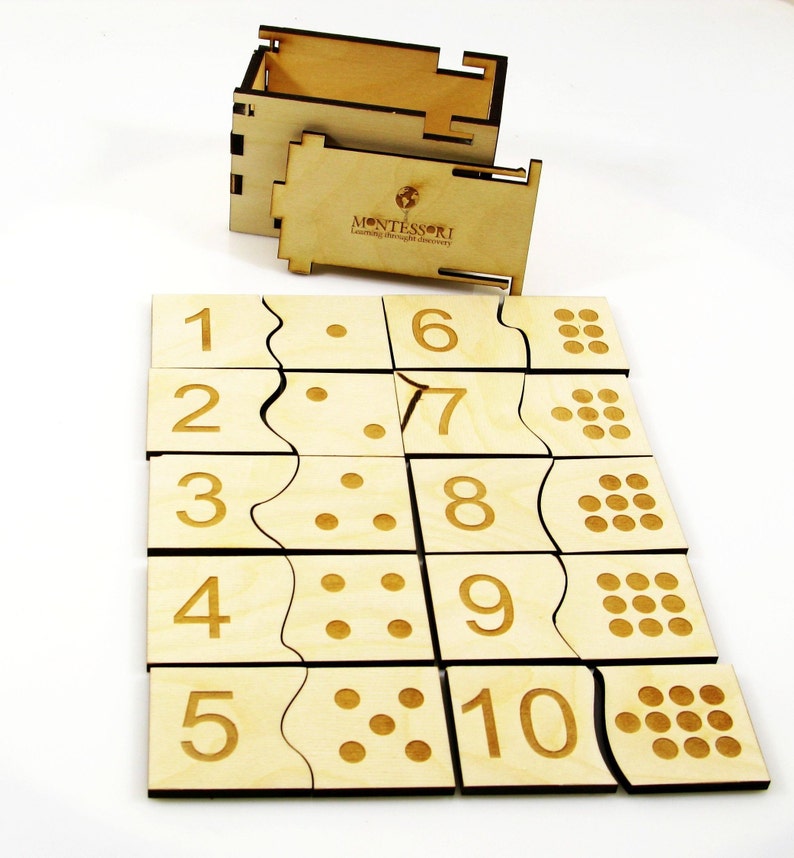 May include: Wooden Montessori number puzzle with a box. The puzzle pieces feature numbers 1 through 10 and corresponding dots. The box has the word "MONTESSORI" printed on it.