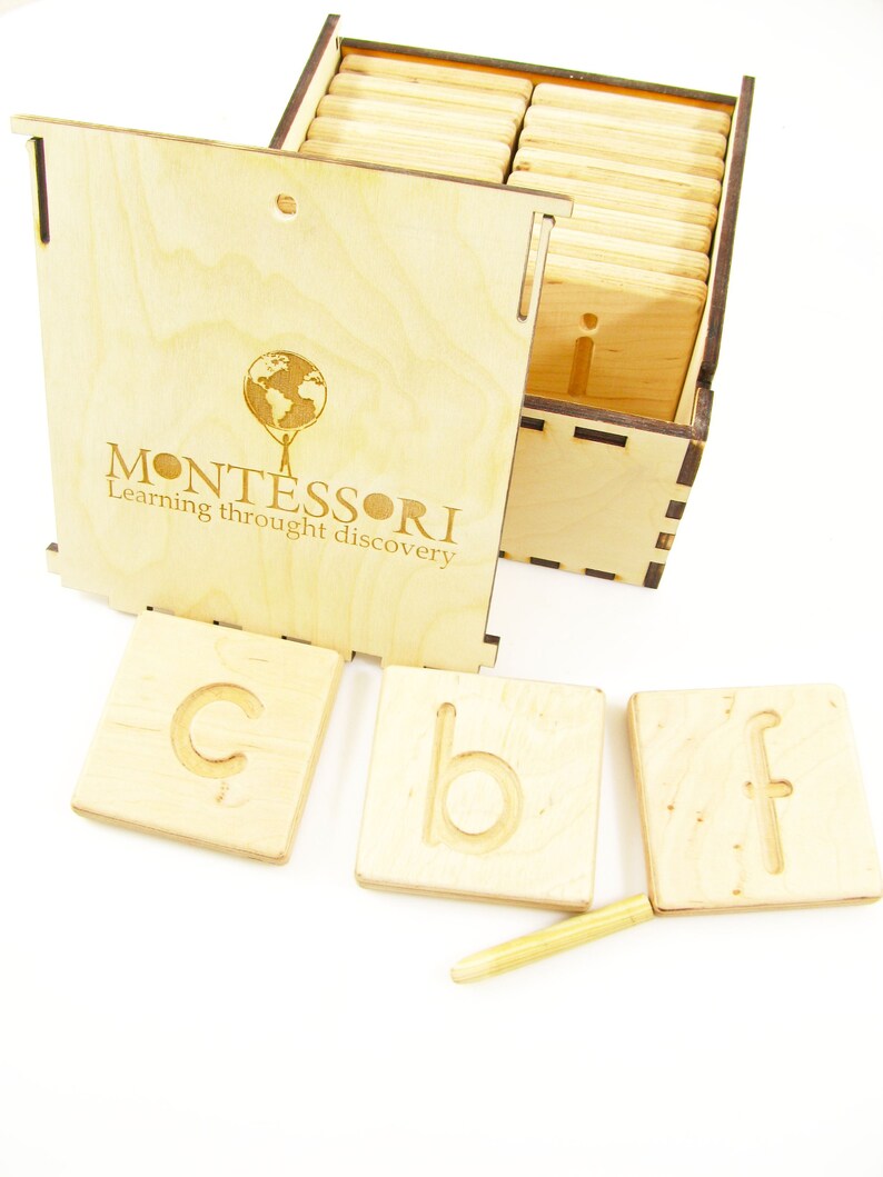 K&ouml;nnte beinhalten: Holzkiste mit einem Montessori-Logo und einem Satz Holzbuchstaben mit erhabenen Buchstaben. Die Buchstaben sind in einer Kiste angeordnet und einige sind aus der Kiste herausgenommen. Ein Holzstift ist ebenfalls enthalten.