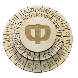 Może przedstawiać: Drewniana szyfrówka z trzema obracającymi się tarczami, każda z literami alfabetu. Tarcza środkowa ma dużą grecką literę Phi.