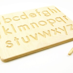 Peut inclure: Planche de tra&ccedil;age en bois de l'alphabet avec un stylet pour s'entra&icirc;ner &agrave; la formation des lettres. La planche pr&eacute;sente l'alphabet entier en lettres majuscules.