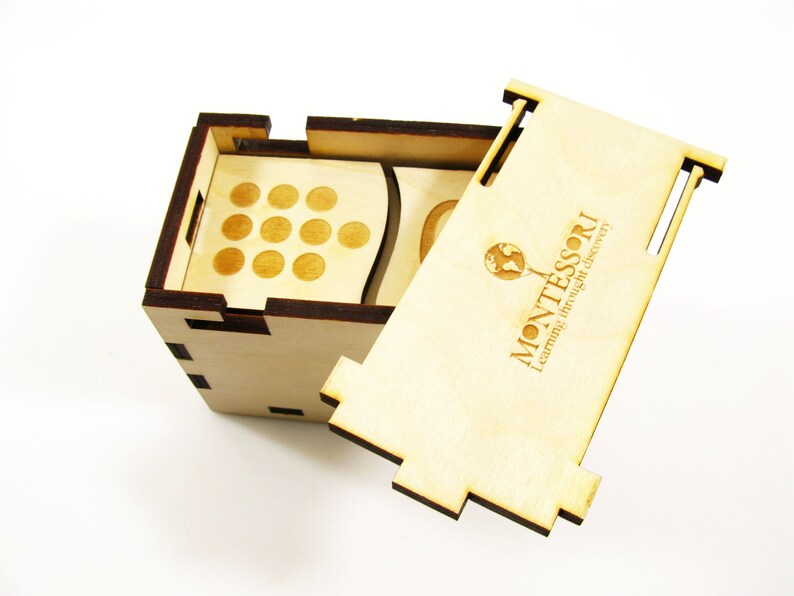 May include: A wooden box with a lid that opens to reveal a set of wooden circles. The box is labeled "MONTESSORI Learning through self discovery".