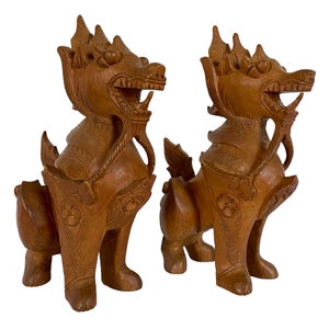 May include: A pair of intricately carved wooden guardian lions, also known as foo dogs, with detailed features and a rich brown color.