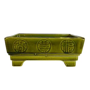 May include: A rectangular, green ceramic planter with three decorative circular emblems. The planter is raised on four short feet. The glossy finish and the symbols give it an Asian-inspired aesthetic.