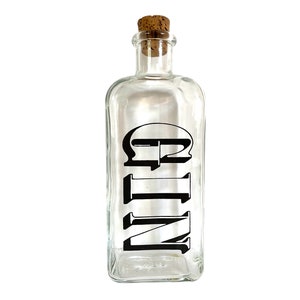 May include: A clear glass bottle with a cork stopper and a black label that says "GIN".