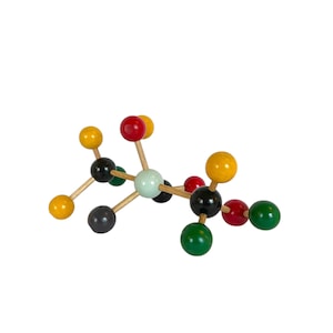 May include: A colorful wooden molecular model with spheres in yellow, red, black, green, and a light blue center. The spheres are connected by wooden rods, creating a three-dimensional structure. This educational tool is used to visualize molecular compounds.