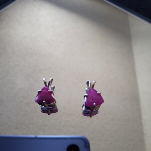 May include: A pair of silver earrings with triangular pink gemstones.