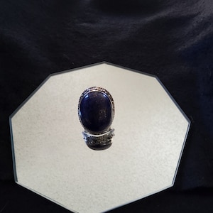 May include: A silver ring with a dark blue oval lapis lazuli gemstone set in a silver bezel.