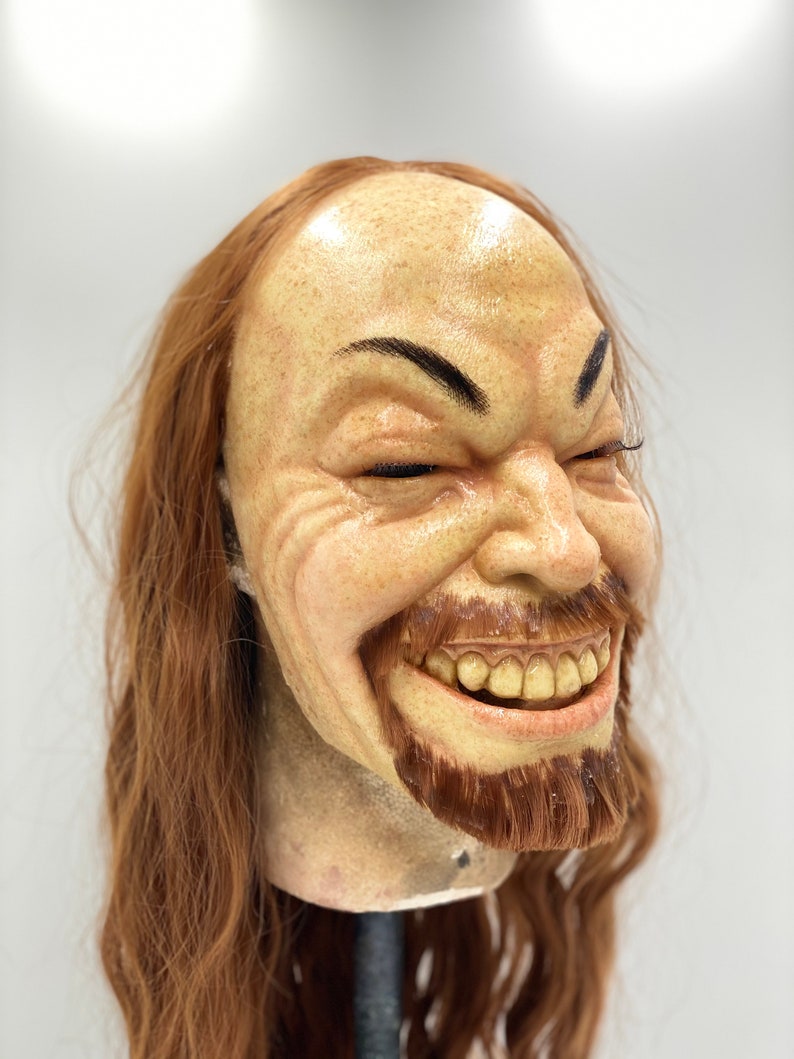 May include: A realistic-looking, hand-crafted, sculpted head with long, brown hair. The head has a wide smile with visible teeth and a brown beard.