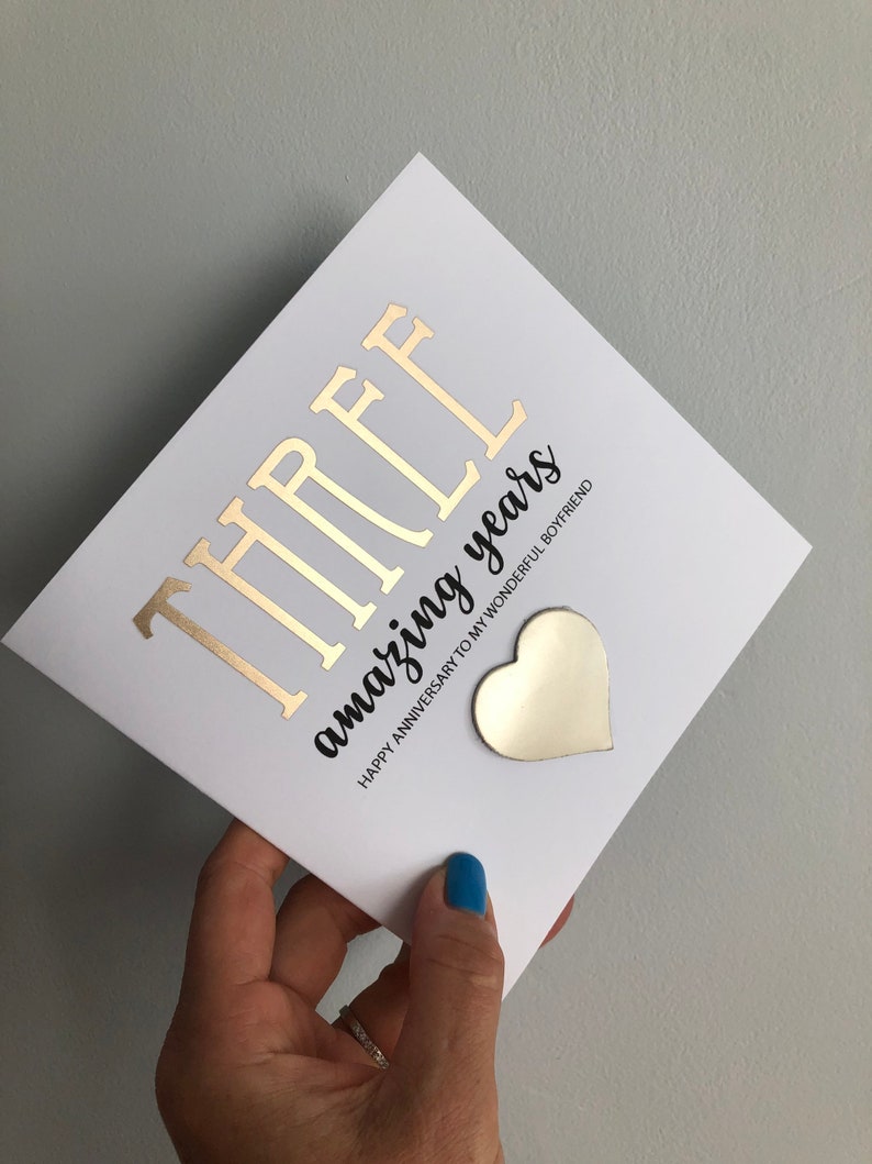 May include: A white card with gold foil lettering that reads "THREE amazing years". The card also has a gold heart sticker with the text "Happy Anniversary to my wonderful boyfriend".