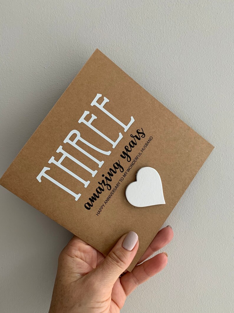May include: A brown card with the text "THREE amazing years" and the words "Happy Anniversary to my wonderful husband". A white heart is attached to the card.