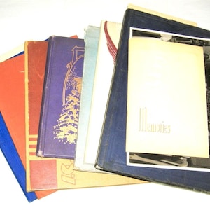 May include: A collection of vintage photo albums with various colored covers, including blue, orange, red, and purple. One album has the word "Memories" on the cover. The albums are arranged in a fan shape.