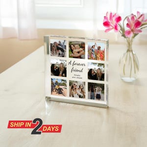 May include: A clear acrylic photo block with nine images of friends. The block has the text "A forever friend" with the names "Amalia and Jessie." A vase of pink flowers is next to it.