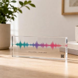 May include: A rectangular clear acrylic block featuring a colorful sound wave graphic that transitions from teal to purple to pink. The text "OUR SONG 14.02.2024" is printed in black below the wave, with a small square QR code in the bottom right corner.
