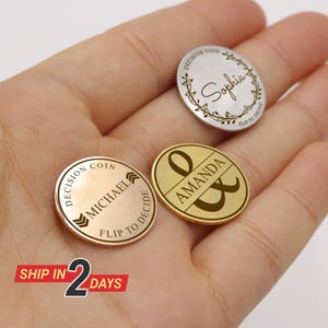 May include: Three personalized decision coins with engraved names and the phrase "Flip to Decide." One coin is gold-toned with "Amanda" and an ampersand. Another is silver with "Sophia" in script. The third is gold-toned with "Michael."
