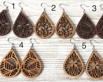 May include: Ten pairs of wooden teardrop earrings with intricate laser cut designs. The earrings are available in five different patterns, each with a unique design. The earrings are made of natural wood and have a warm, earthy tone.