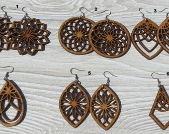 May include: Six pairs of wooden earrings with intricate laser-cut designs. The earrings are in various shapes, including circles, ovals, and triangles. The designs feature geometric patterns and floral motifs. The earrings are brown in color and have silver hooks.