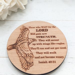 Pu&ograve; includere: Un cartello rotondo in legno con un'immagine di un'aquila in volo incisa al laser. Il cartello presenta il testo "Those who WAIT for the LORD Will gain new STRENGTH. They will mount up with wings like eagles. They'll run and not get tired. They will walk and not become weary. Isaiah 40:31"