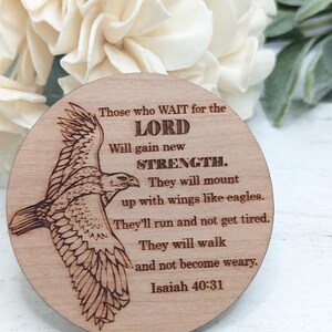 Pu&ograve; includere: Un cartello rotondo in legno con un design di aquila marrone e il testo "Those who WAIT for the LORD Will gain new STRENGTH. They will mount up with wings like eagles. They'll run and not get tired. They will walk and not become weary. Isaiah 40:31"
