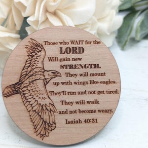 Pu&ograve; includere: Un cartello rotondo in legno con un'immagine di un'aquila in volo incisa a fuoco. Il cartello contiene un versetto biblico di Isaia 40:31, "Quelli che aspettano il SIGNORE rinnoveranno le loro forze; monteranno con ali come aquile; correranno e non si stancheranno, cammineranno e non si affaticheranno. Isaia 40:31"