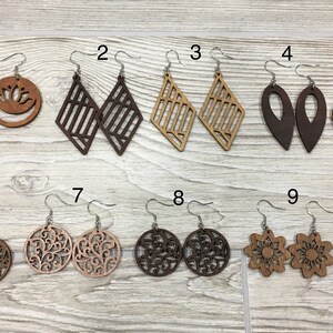 Peut inclure: Dix paires de boucles d'oreilles en bois avec différents motifs, y compris des formes géométriques, des feuilles et des motifs floraux. Les boucles d'oreilles sont présentées sur une surface en bois.
