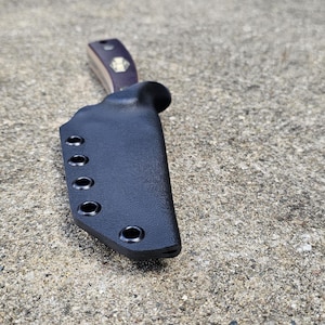 May include: Black leather knife sheath with multiple snap closures.