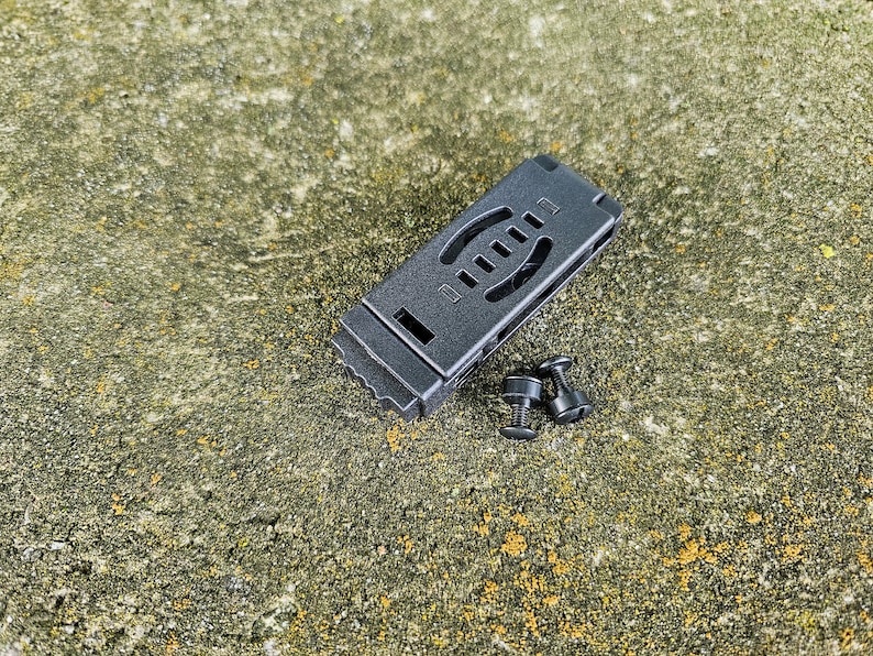 May include: Black plastic clip with two black screws. The clip has a textured surface and a series of holes.