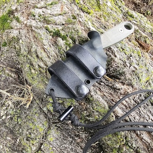 May include: A black leather knife sheath with a snap closure and a black paracord lanyard. The sheath is designed to fit a small fixed blade knife.