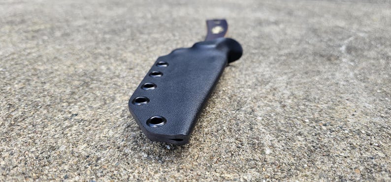 May include: Black leather knife sheath with multiple holes for belt attachment.