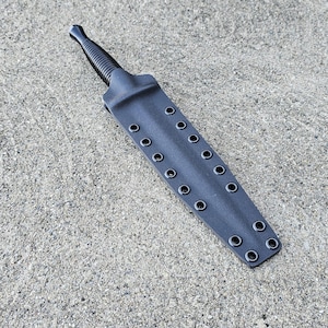 Puede incluir: Una funda de cuero negra con una fila de ojales metálicos para un cuchillo.