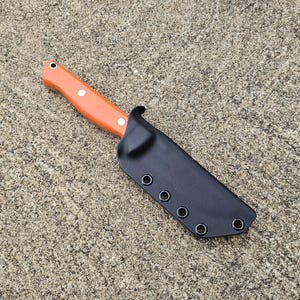May include: An orange-handled knife with a black sheath. The knife handle has three white rivets and a lanyard hole. The black sheath has five eyelets. The knife is designed for outdoor use.
