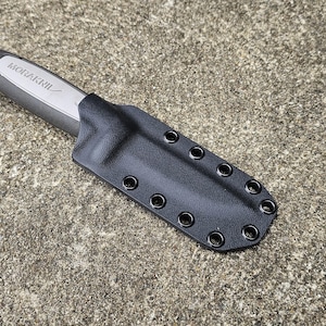 May include: A black knife with a gray handle and a black sheath. The knife handle has the brand name "MORAKNIV" printed on it. The sheath has multiple eyelets along the edge.