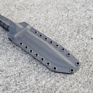May include: Black knife sheath with multiple snap closures. The sheath is made of a durable material and has a sleek design.