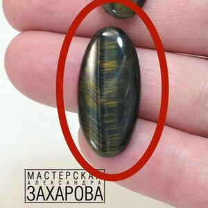 May include: Oval shaped cabochon gemstone with a tiger's eye pattern in shades of brown, gold, and blue.