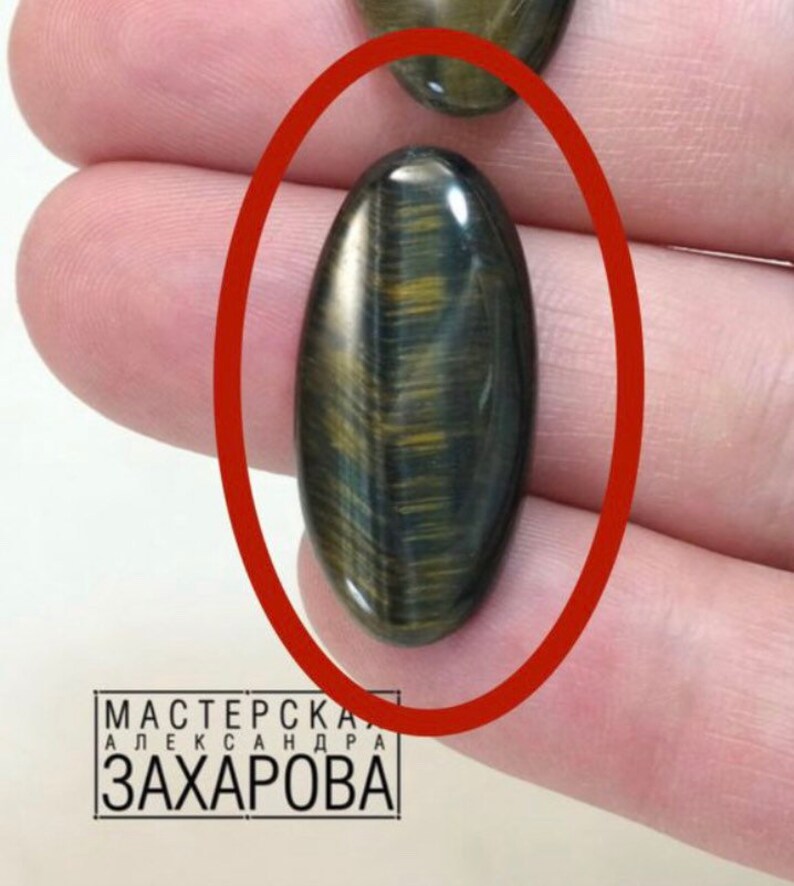 May include: Oval shaped cabochon gemstone with a tiger's eye pattern in shades of brown, gold, and blue.