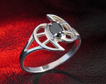 May include: A silver ring with an intricate design featuring a black gemstone. The ring is set against a red background.
