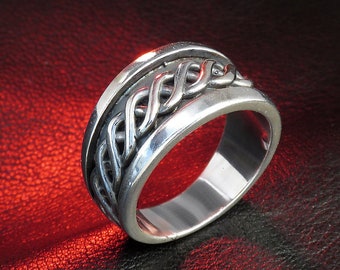 Puede incluir: Un anillo de plata con un diseño trenzado. El anillo está sobre un fondo de cuero rojo.
