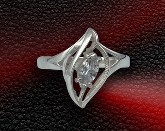 Peut inclure: Une bague en argent avec une pierre précieuse transparente sertie dans un design abstrait unique.