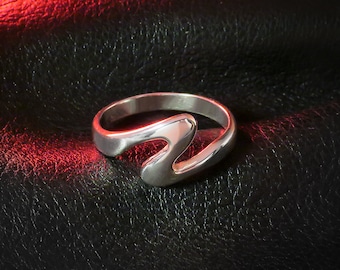 May include: A silver ring with a unique, abstract design. The ring is made of a smooth, polished metal and has a modern, minimalist style.