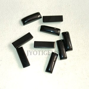 May include: Ten black rectangular gemstone cabochons. The cabochons are smooth and polished.