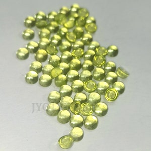 May include: A pile of small, round, translucent green cabochons. The cabochons are smooth and have a slightly pearlescent sheen.