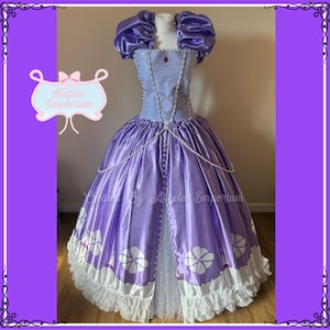 May include: A purple satin ball gown with a white lace trim and a pearl necklace. The bodice is decorated with a silver and purple design and a large purple gem. The skirt is full and flowing with a white tulle underskirt. The dress is made by Angels Emporium.