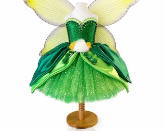 May include: A green fairy costume featuring a sequined bodice, a layered tulle skirt with glitter accents, and large translucent yellow and green wings. The dress is adorned with yellow floral details, green fabric leaves, and white faux fur trim.