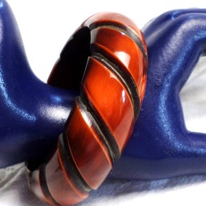 May include: A red and black plastic bangle bracelet with a twisted design.