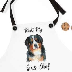 May include: White apron with black straps and buttons. A watercolor illustration of a Bernese Mountain Dog with the text "Meet My Sous Chef" printed on the apron.