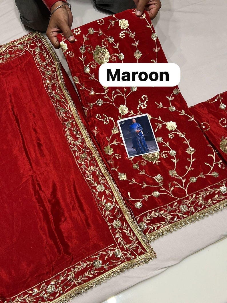May include: Maroon fabric with gold floral embroidery and trim. The fabric appears to be velvet. The word "Maroon" is displayed in a white rectangular box. A small image of a person wearing a blue outfit is also visible.