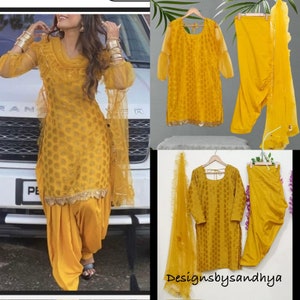 May include: A bright yellow three-piece outfit consisting of a long-sleeved tunic with a subtle tonal pattern, matching pleated trousers, and a sheer ruffled dupatta. The tunic features a scalloped hem with metallic gold trim detailing.