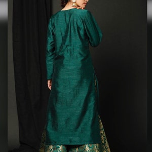 May include: A long, teal green kurta with long sleeves and a matching teal green skirt with a gold brocade pattern.